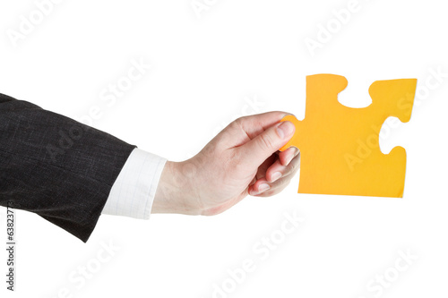 male hand holding big yellow paper puzzle piece