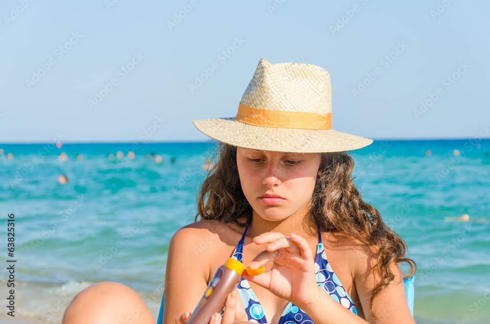 Girl applying sun cream on the beach