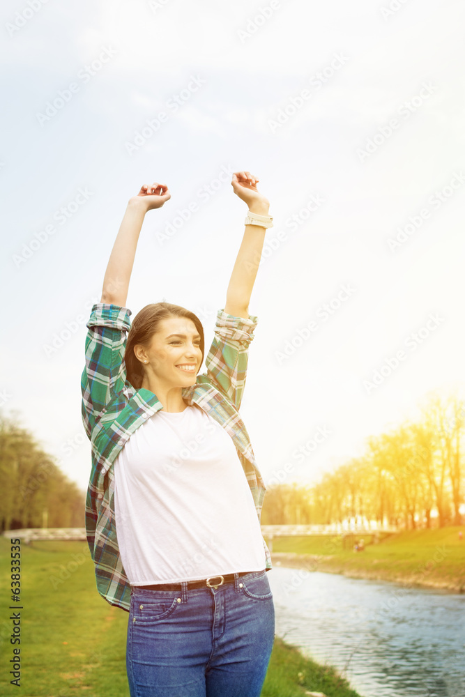 Happy young woman with hands raised standing by the river Happy young woman with hands raised standing by the river