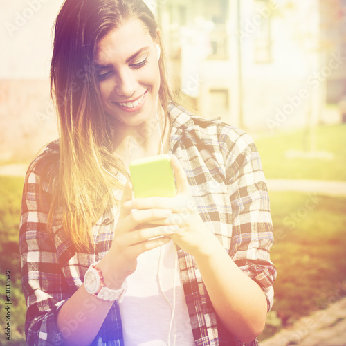 Beautiful happy teenage girl with phone texting photo
