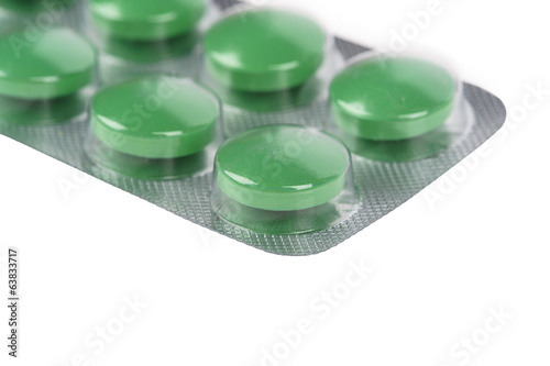 Green pills in blisters on white background