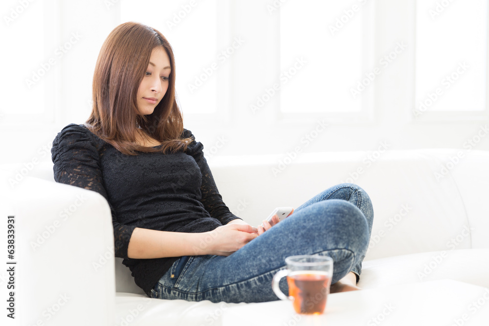 Obraz premium 部屋でスマートフォンを見る女性