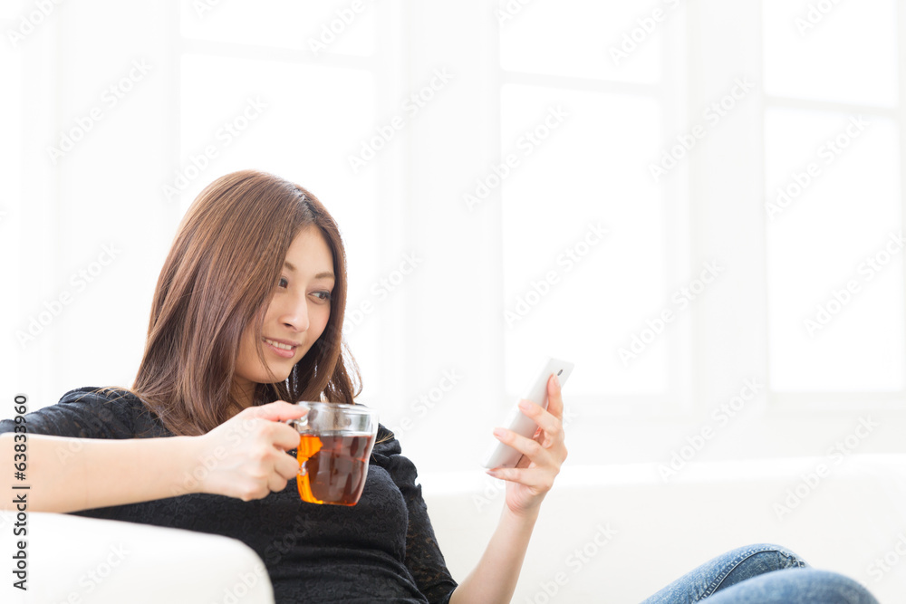 部屋でスマートフォンを見る女性