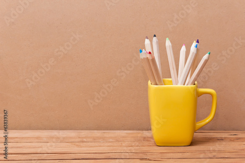 Color pencil in the cup on wooden background