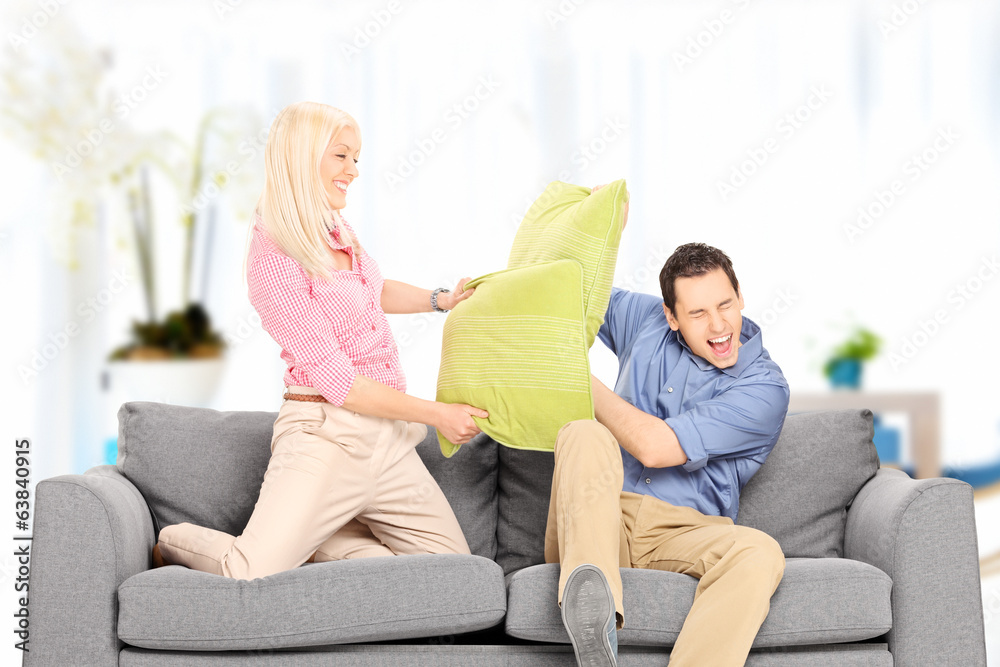 Young couple fighting with pillows at home