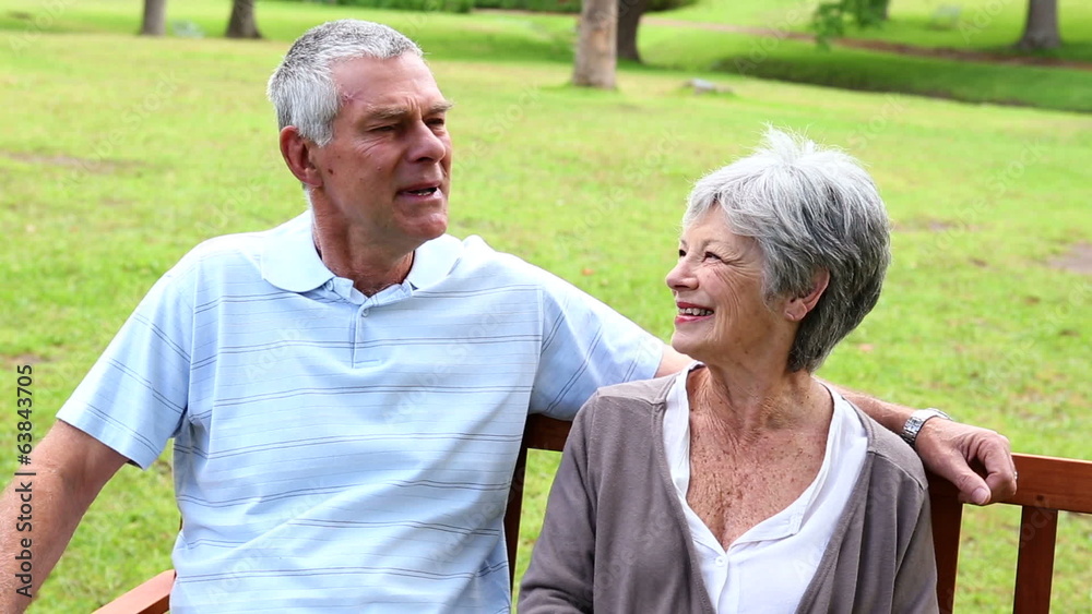 Retired couple sitting on a park bench talking Retired couple sitting on a park bench talking
