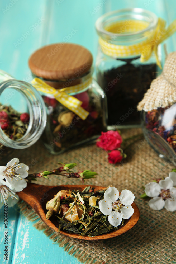 Assortment of herbs and tea in glass jars on wooden background