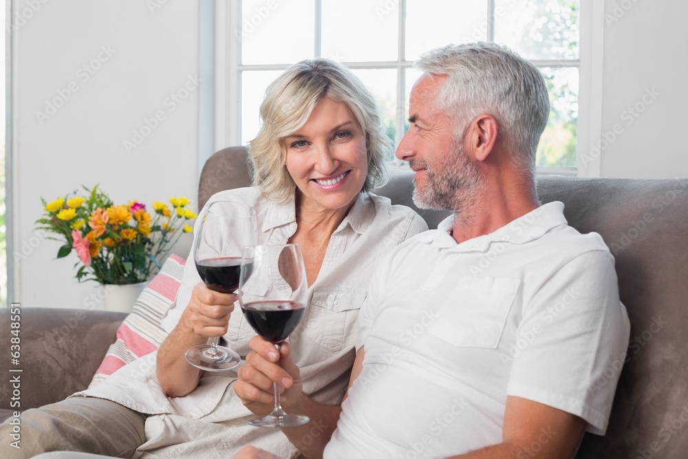 Happy loving mature couple with wine glasses in living room Happy loving mature couple with wine glasses in living room