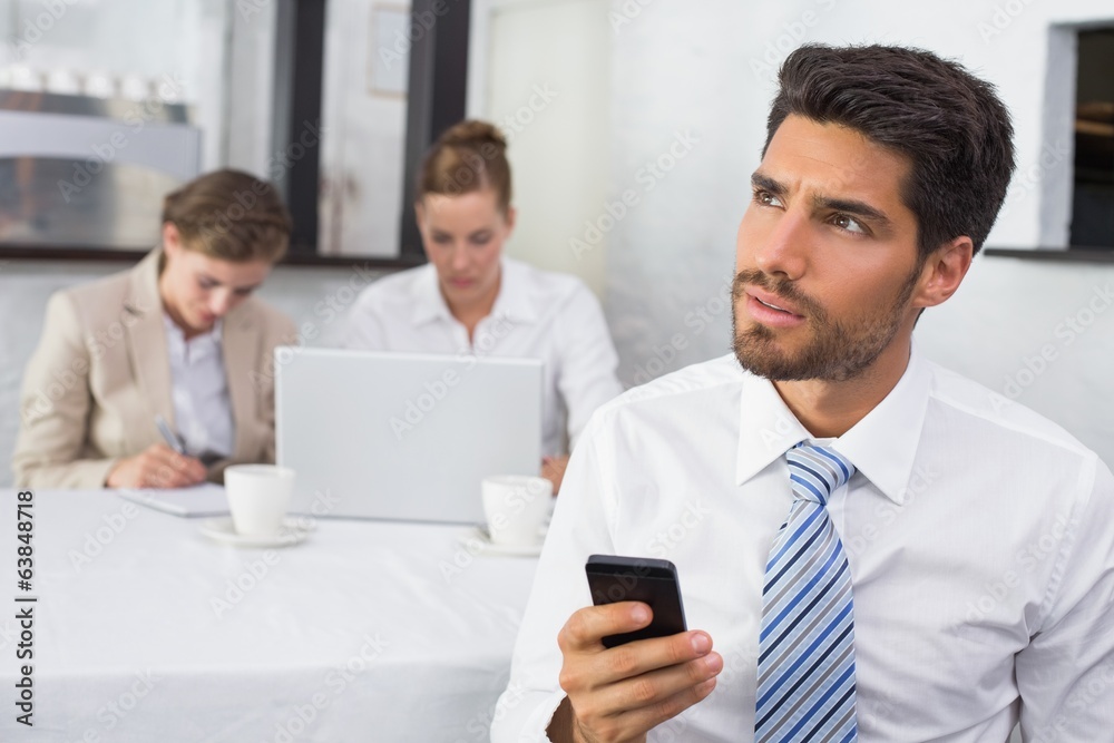 Businessman text messaging with colleagues at office desk Businessman text messaging with colleagues at office desk