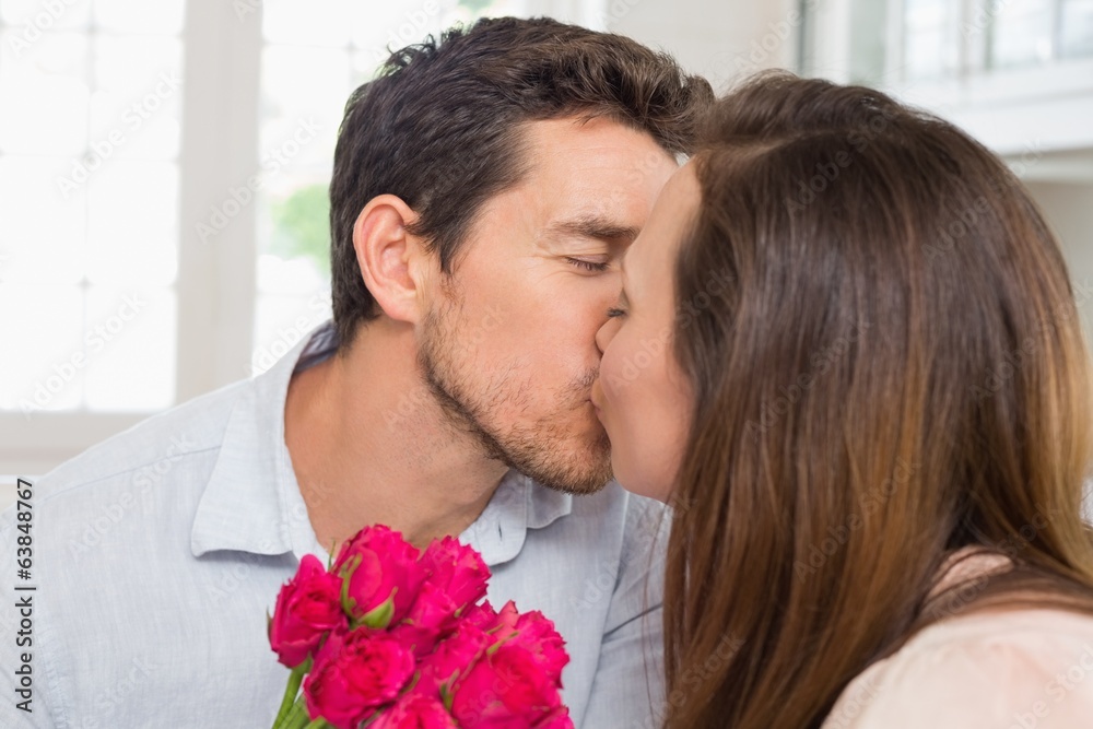 Close-up of a loving couple kissing with flowers Close-up of a loving couple kissing with flowers