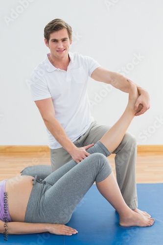 Personal trainer lifting pregnant clients leg