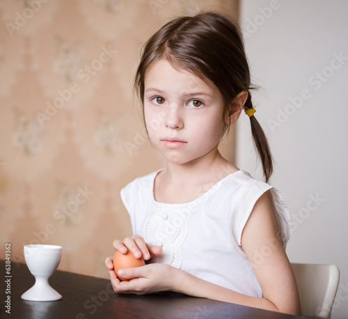 Serious prescholler girl holding egg in her hands photo