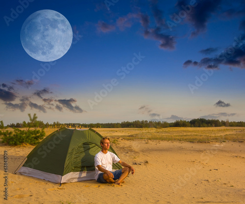 man sit near a tent at the evening