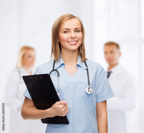 smiling female doctor or nurse with clipboard