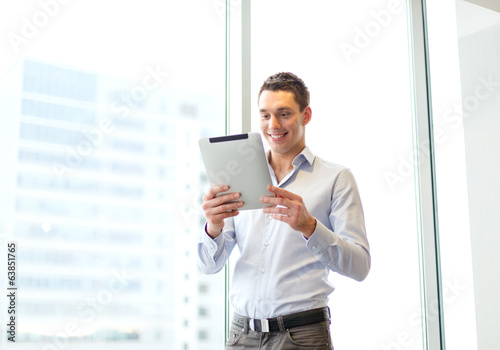 smiling businessman with tablet pc in office