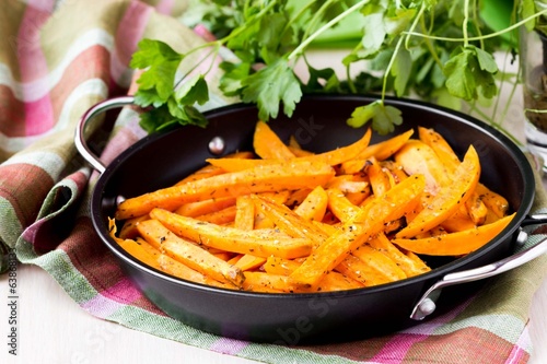 Sweet potatoes, batata, sliced, fried in pan with spices, herb