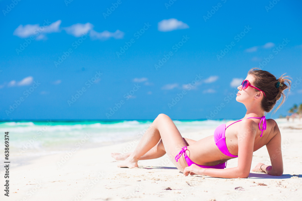 front view of long haired young woman in bikini lying on