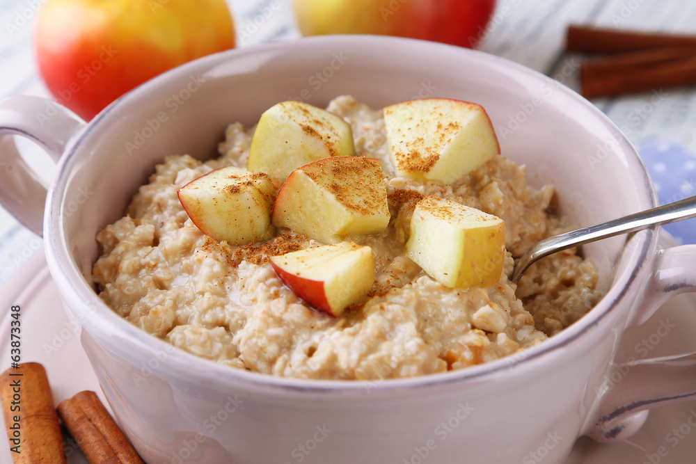 Tasty oatmeal with apples and cinnamon on wooden table Tasty oatmeal with apples and cinnamon on wooden table