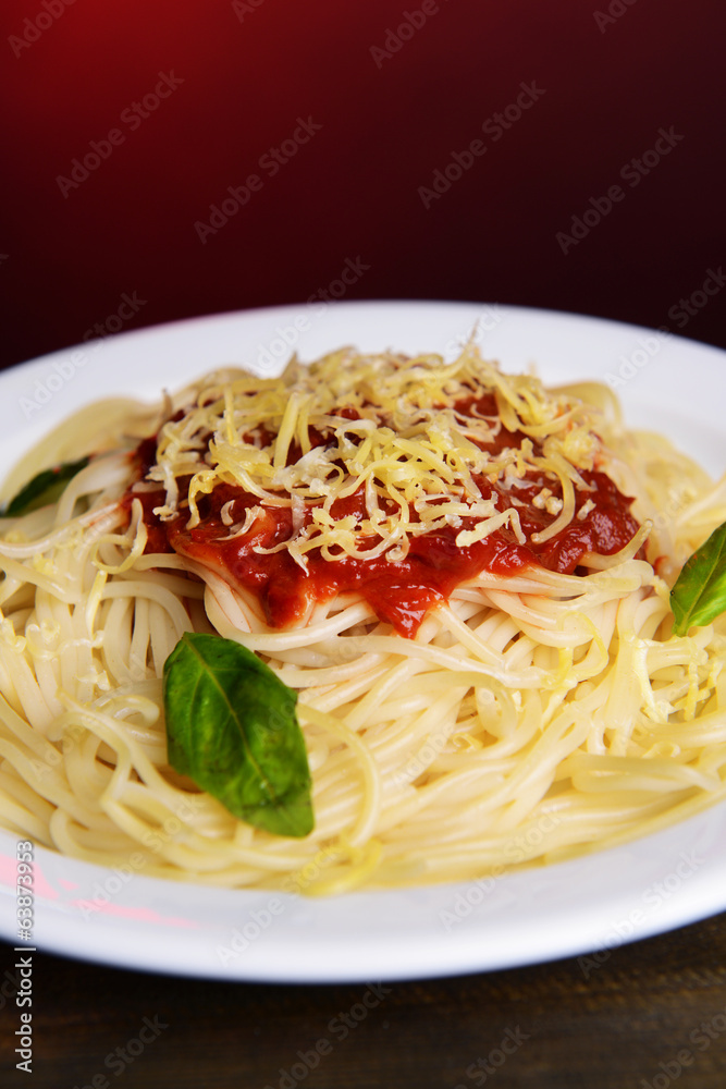 Pasta with tomato sauce on plate on table on red background Pasta with tomato sauce on plate on table on red background