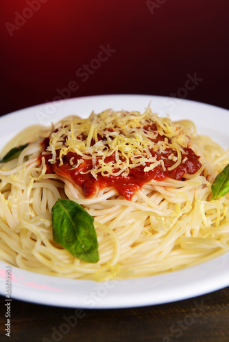 Pasta with tomato sauce on plate on table on red background