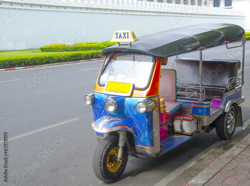 A three wheeled tuk tuk taxi on a street in Bangkok