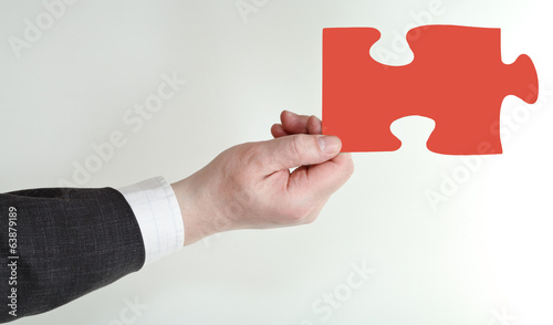 male hand holding red puzzle piece