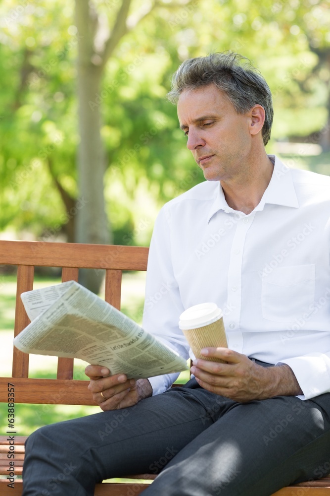 Fototapeta premium Businessman reading newspaper in park