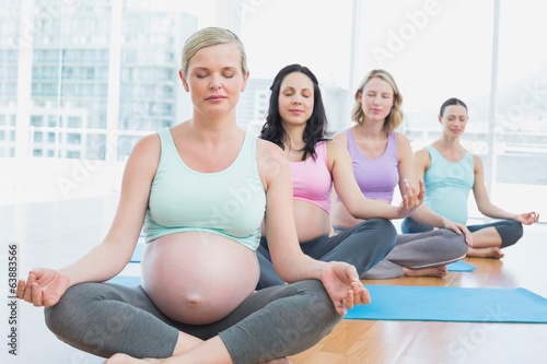 Pregnant women in yoga class sitting on mats with eyes closed