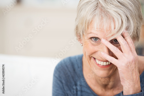 lächelnde seniorin fasst sich an den kopf