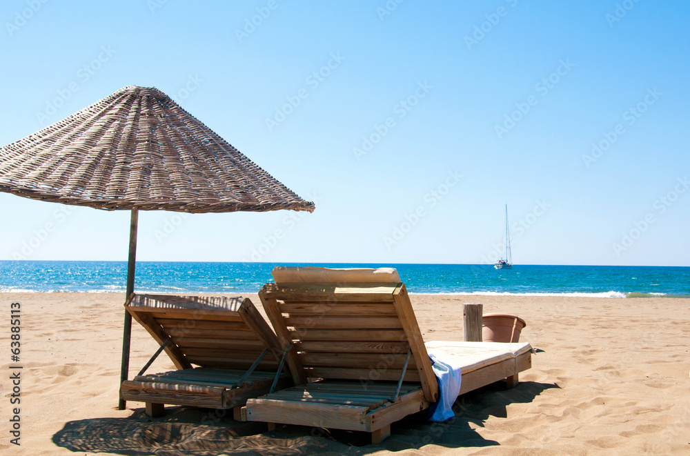 Sunbeds and rattan parasols on sandy seaside.