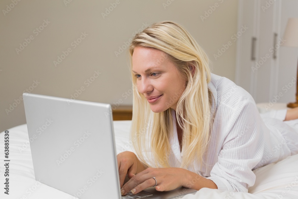 Woman using laptop while lying in bed Woman using laptop while lying in bed