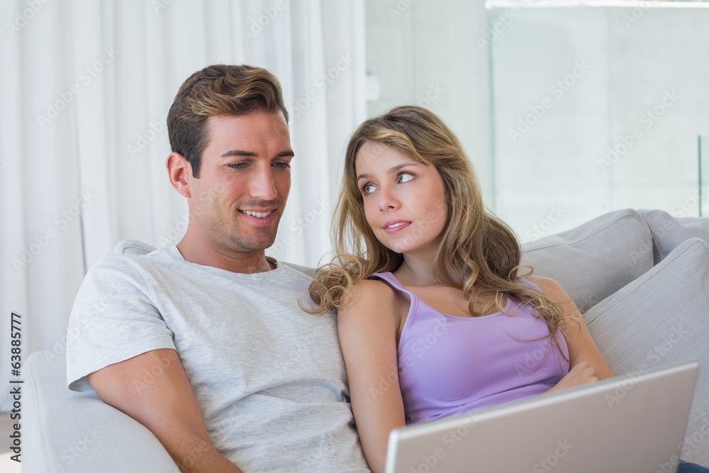 Relaxed couple using laptop on couch Relaxed couple using laptop on couch