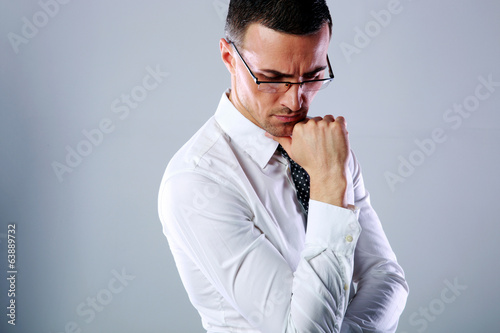Portrait of a pensive man in glasses on gray background