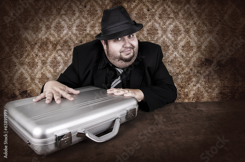 Принти на полотні Vintage-style image of a man in a fedora and suit, guarding a silver briefcase