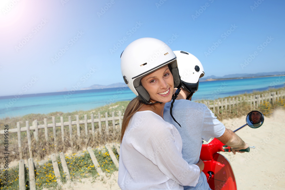 Naklejka premium Cheerful girl riding moto with boyfriend by the beach