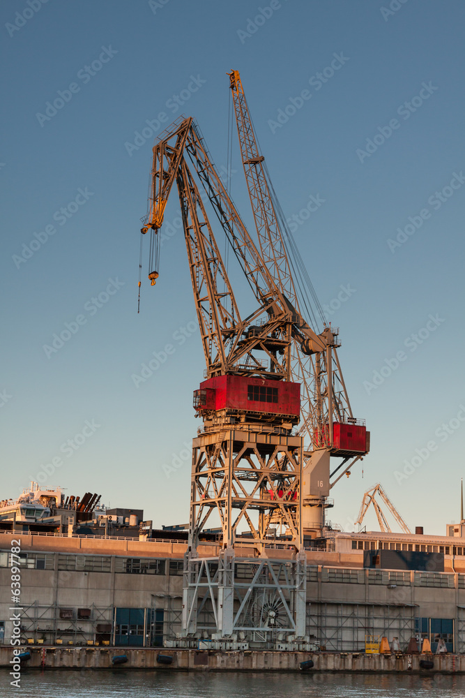 sea port cranes with blue cloudy sky in background and water in