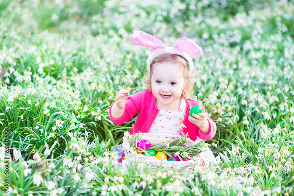 Cute toddler girl wearing bunny ears playing with Easter eggs Cute toddler girl wearing bunny ears playing with Easter eggs