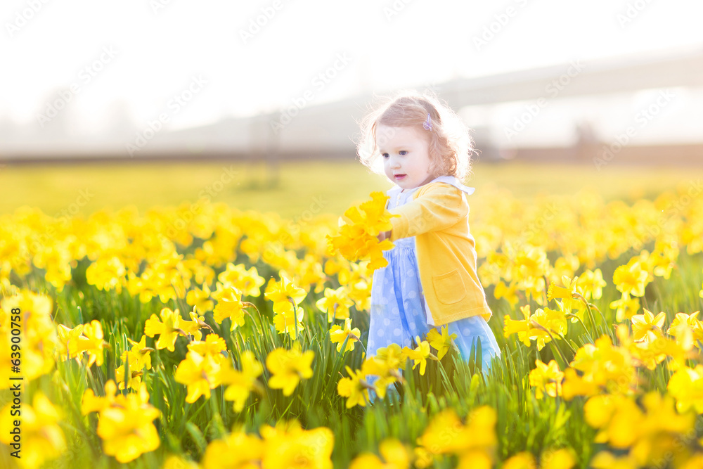 Pretty toddler girl in blue dress walking on flower's field Pretty toddler girl in blue dress walking on flower's field