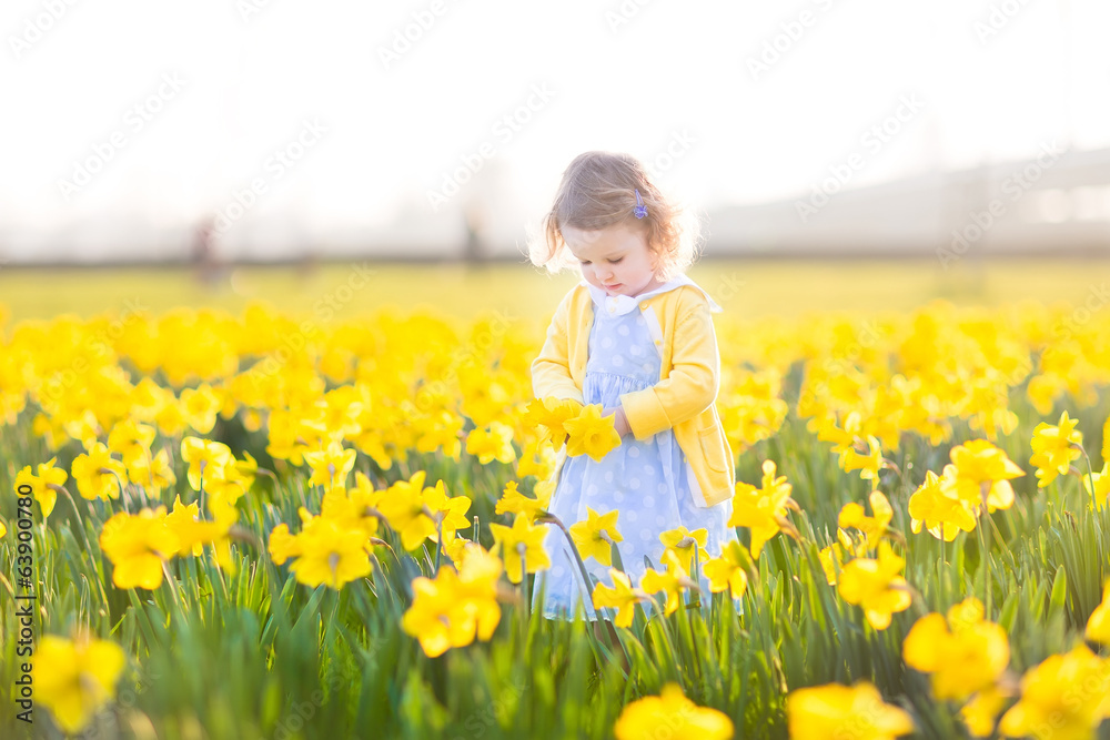 Little toddler girl in a blue dress playing in a meadow Little toddler girl in a blue dress playing in a meadow