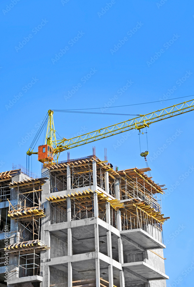 Crane and building construction site against blue sky