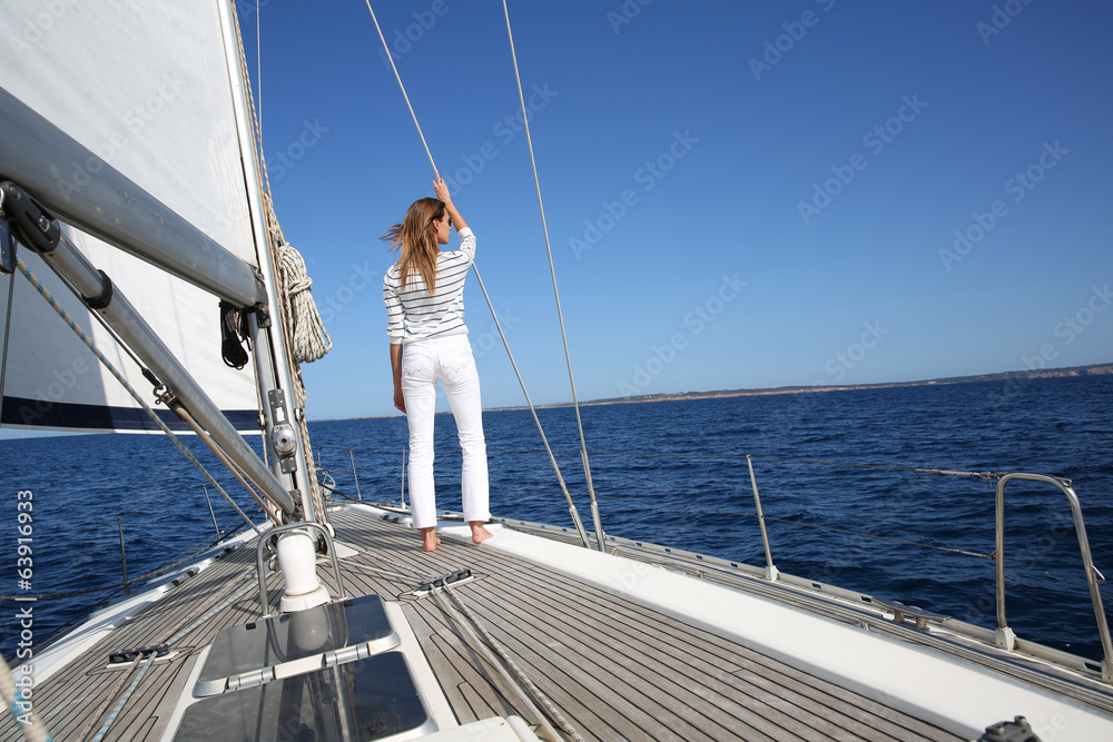 Fototapeta premium Attractive woman standing on sailboat deck