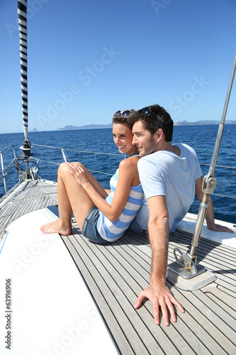Couple stting on sailboat deck looking at sealine