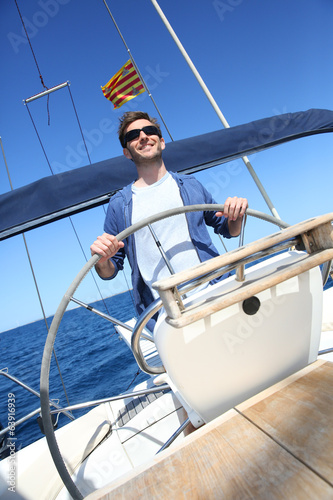 Skipper on sailboat navigating in mediterranean sea