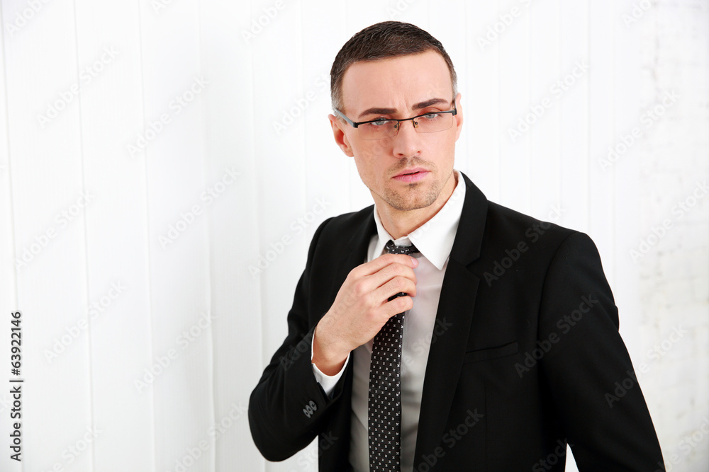 Handsome businessman in glasses adjusting his tie