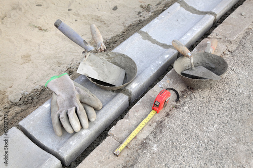 Curb stone, mason tools trowel gloves meter at construction site