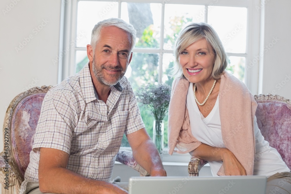 Smiling mature couple using laptop at home Smiling mature couple using laptop at home