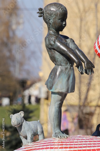 Billede på lærred Old bronze statue of girl with dog in the park