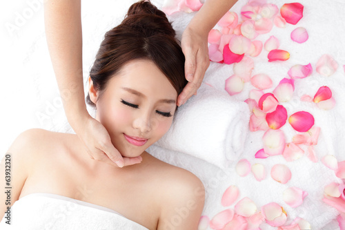 woman enjoy receiving face massage at spa with roses