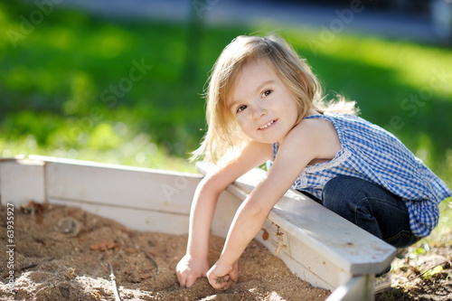 Adorable girl playing in a sandbox photo