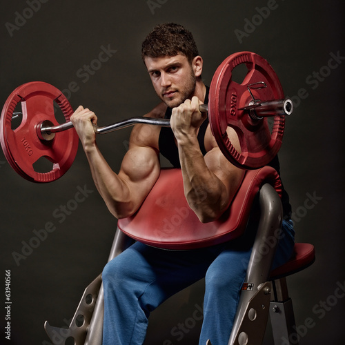 athletic young man lifting weights photo